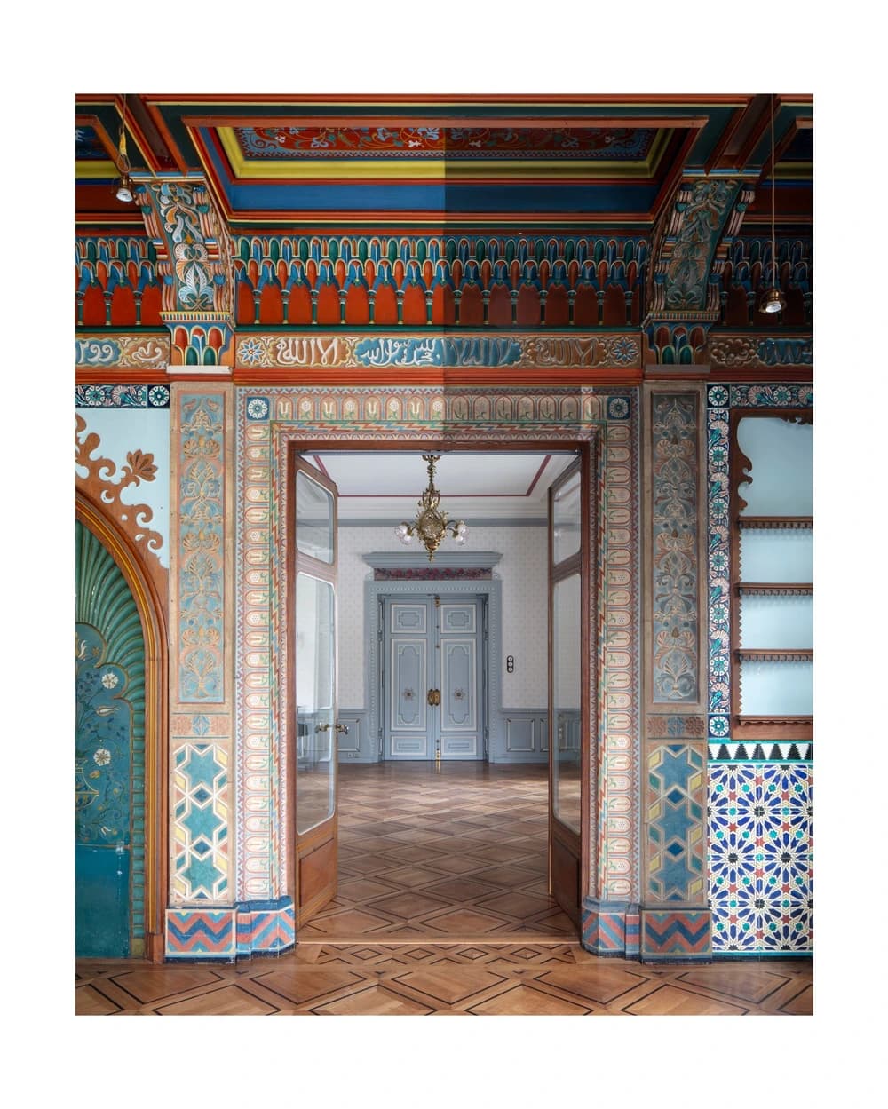 Une porte richement ornée du Salon mauresque à Neuchâtel, entourée de bois peint, de stucs et de surfaces en céramique décorative.